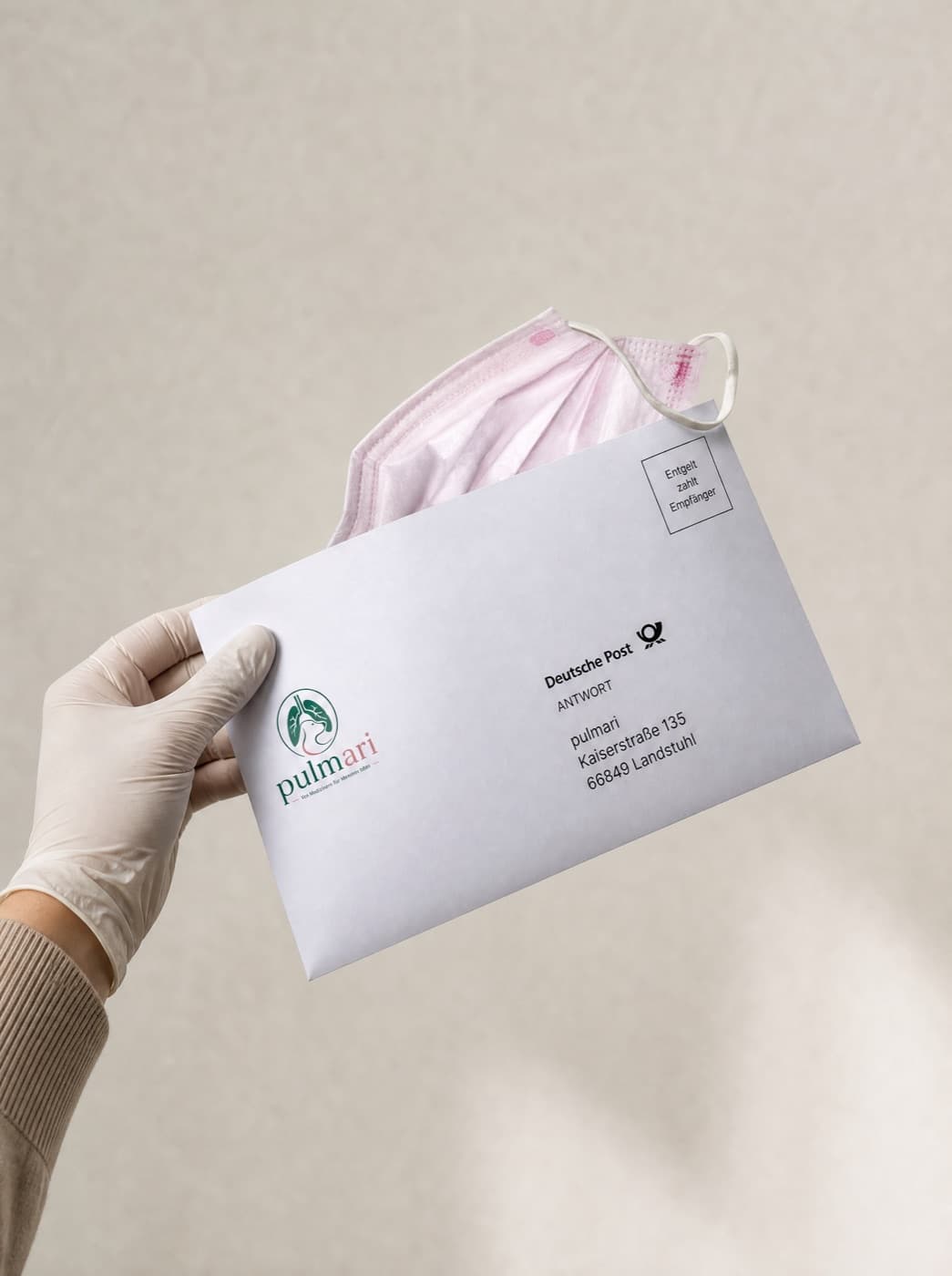 Hand legt die Pulmari Atemmaske in den vorfrankierten Deutsche-Post-Rückumschlag